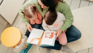 Nainen lukee kirjaa kahdelle lapselle.